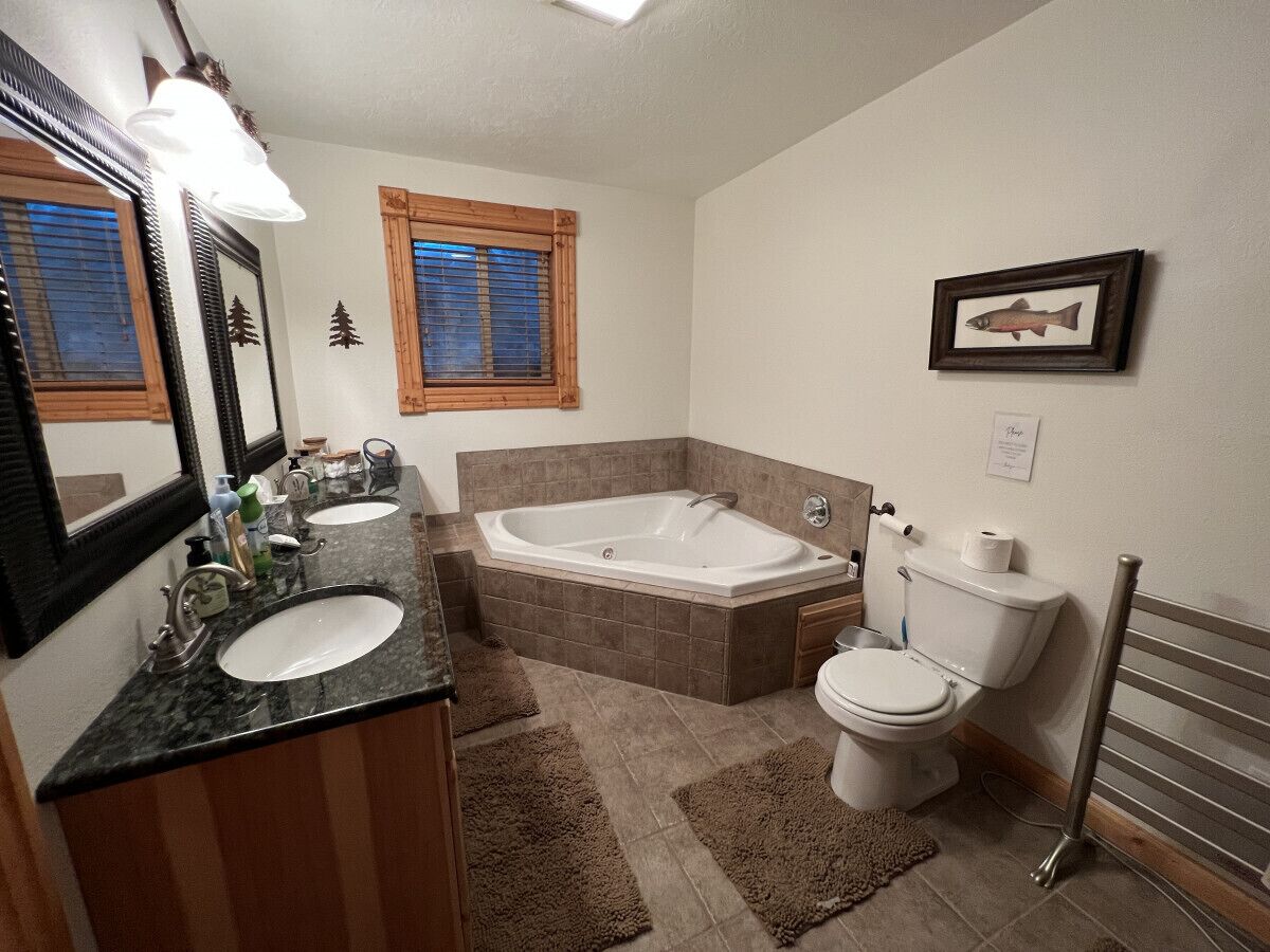 A bathroom with a bathtub, two sinks, a toilet, and a towel rack.