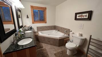 A bathroom with a bathtub, two sinks, a toilet, and a towel rack.