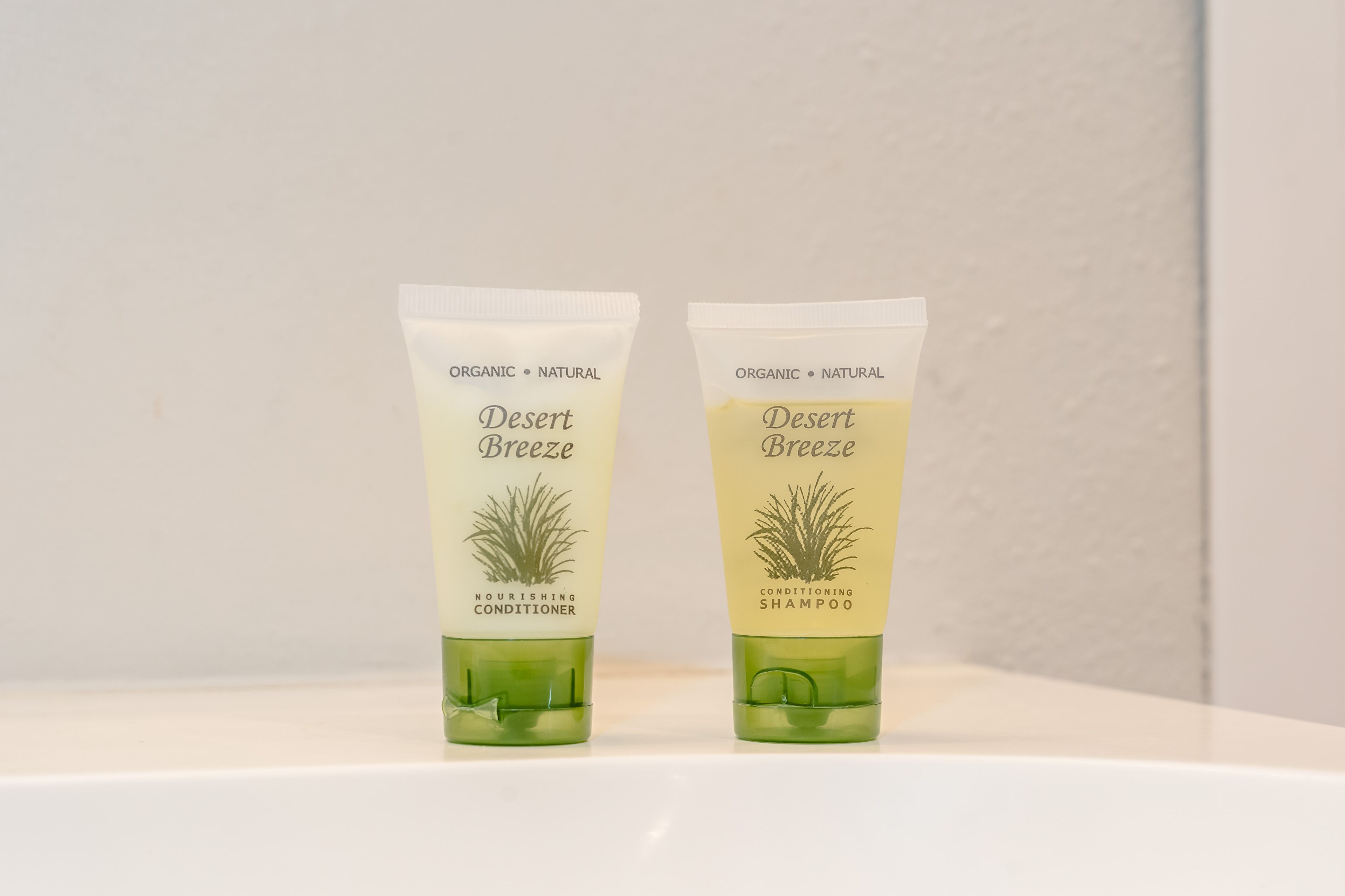 Two tubes of Desert Breeze organic shampoo and conditioner on a white surface.