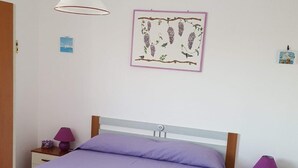 Ein Schlafzimmer mit Bett, Nachttischen, einer Hängelampe und einem gerahmten Bild an der Wand.