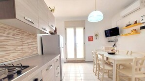 Eine moderne Küche mit einem Gaskochfeld, einem Kühlschrank und einem Essbereich mit Tisch und Stühlen.