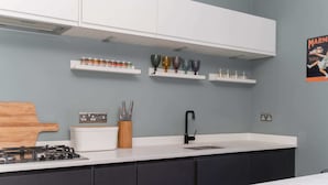 Eine moderne Küche mit weißen Schränken, einem schwarzen Wasserhahn und einer Arbeitsplatte mit Gläsern und Einmachgläsern.
