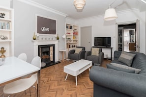 A modern living room with a fireplace, a television, and a bookshelf.