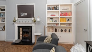 Ein Wohnzimmer mit Kamin, Bücherregal und grauem Sofa.
