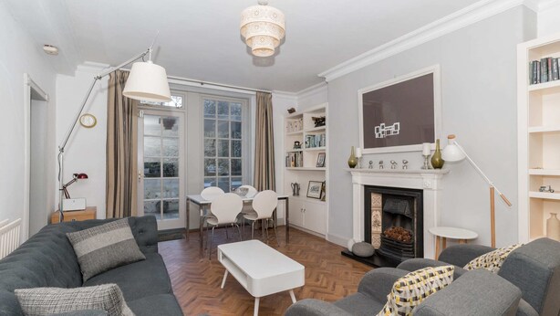 Ein modernes Wohnzimmer mit einer Couch, Sesseln, einem Couchtisch, einem Kamin und einem Essbereich mit Stühlen und einem Tisch.