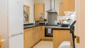 Una cucina con mobili in legno, una cappa in acciaio inossidabile, una lavastoviglie e un frigorifero.