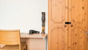 Una stanza con una scrivania in legno, una sedia, un armadio e un vaso sulla scrivania.