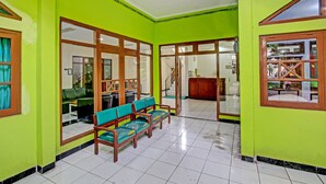 A waiting area with green walls, wooden benches, and large glass doors leading to another room. - SPOT ON 91471 Syariah Wisma Uin Walisongo (Semarang)