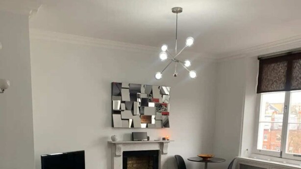 Un salon moderne avec une cheminée, une table basse en verre ornée de fleurs et un téléviseur.