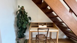 Uma mesa de madeira com uma cadeira, um vaso de planta e uma escada de madeira.