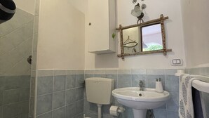 A bathroom with a toilet, sink, and shower area.