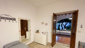 A bedroom with a bed, a dresser, a mirror, and a door leading to a balcony.