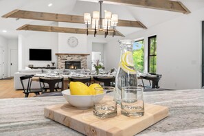 A dining area with a wooden table, chairs, a chandelier, and a fireplace. - Luxury Helen Cabin Near Wineries, Chef’s Kitchen, 4 Ensuites, Hot Tub, Game Room (Sautee Nacoochee)