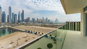A modern building with a glass balcony overlooking a beach and a city skyline.