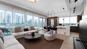 A modern living room with a sofa, coffee table, and a city view through large windows.