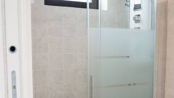 A glass-enclosed shower stall with a white toilet and a towel rack.