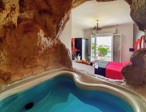 Una stanza con piscina, un letto, un lampadario e vista sulla città.