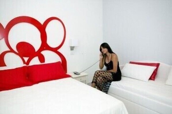 A hotel room with a bed, a bedside table, and a red abstract wall art piece. - Hotel Coelho (Gatteo)