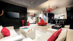 Een moderne woonkamer met witte banken en rode accenten, een flatscreen televisie en een bar met een piano.
