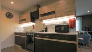 Een moderne keuken met een centraal eiland, een ingebouwde oven, magnetron en een klok aan de muur.