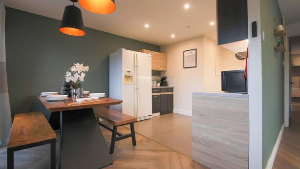 Een moderne keuken met een houten tafel, een koelkast en een magnetron.
