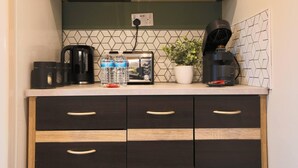 Een keuken met een koffiezetapparaat, broodrooster en waterflessen op het aanrecht.