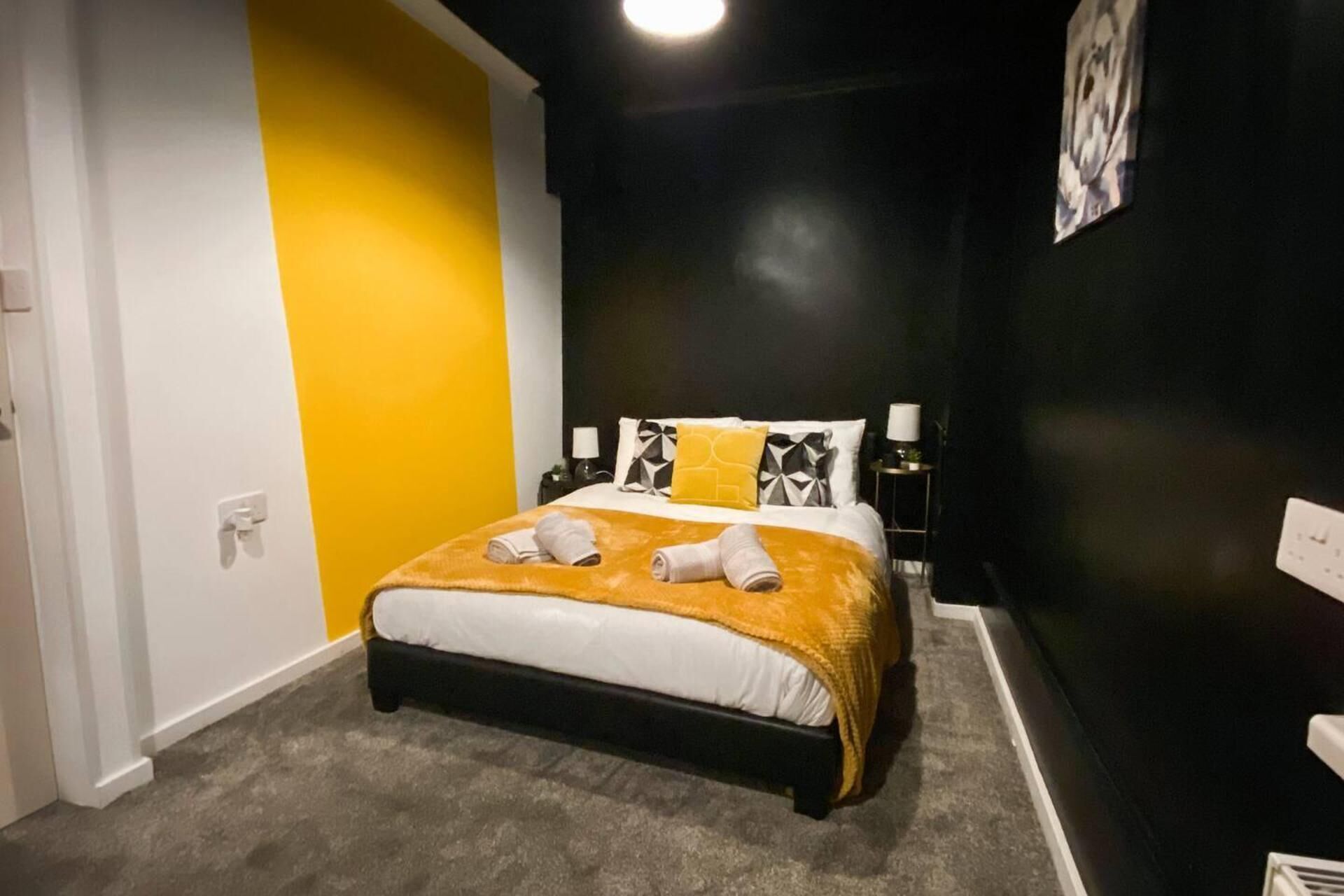 A hotel room with a bed, a nightstand, and a wall-mounted artwork.