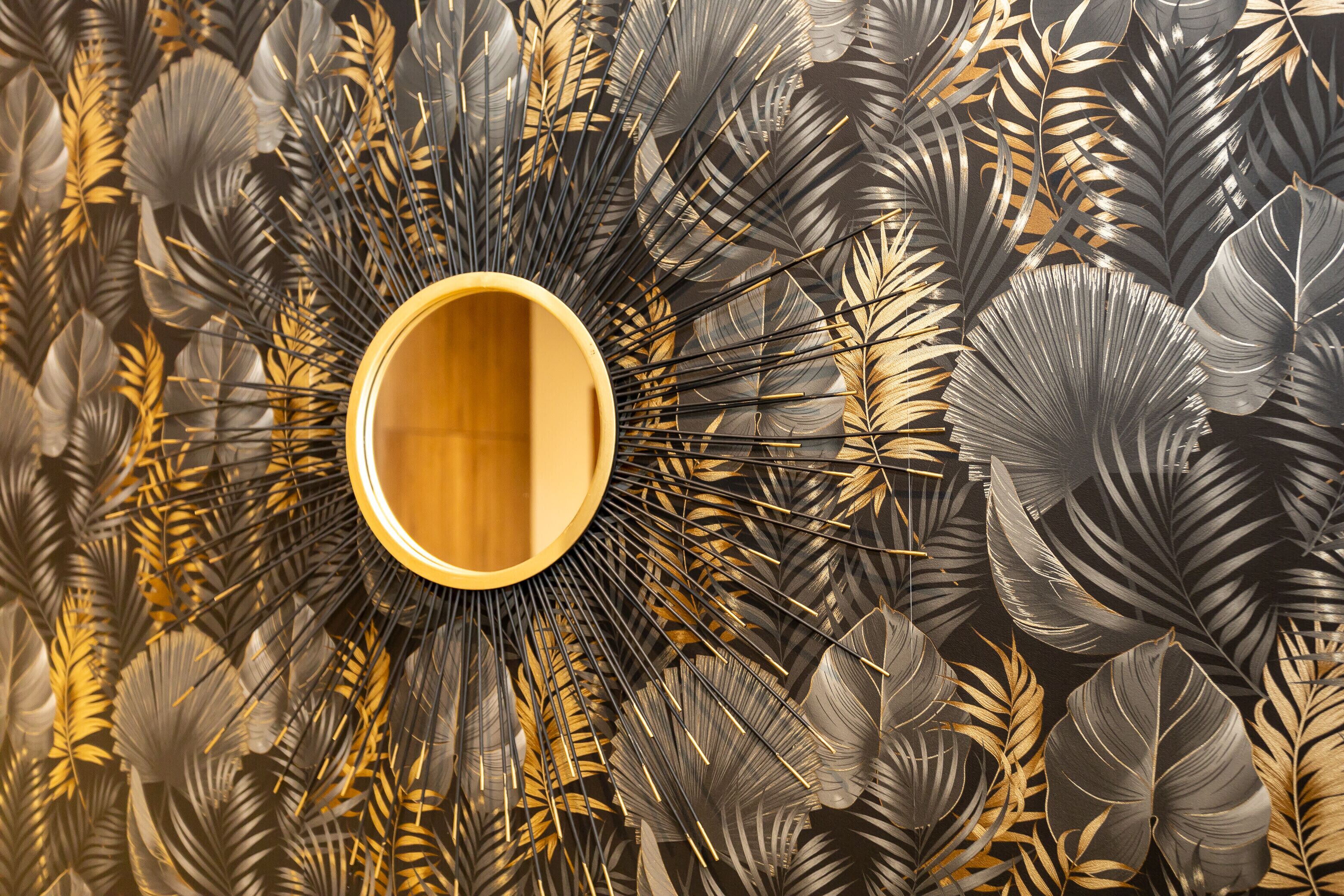 A wall with a circular wooden panel surrounded by a pattern of large, dark leaves.