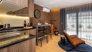 Une cuisine moderne avec un mur d’accent en bois, un coin repas avec une table et des chaises, et une grande fenêtre avec des rideaux.