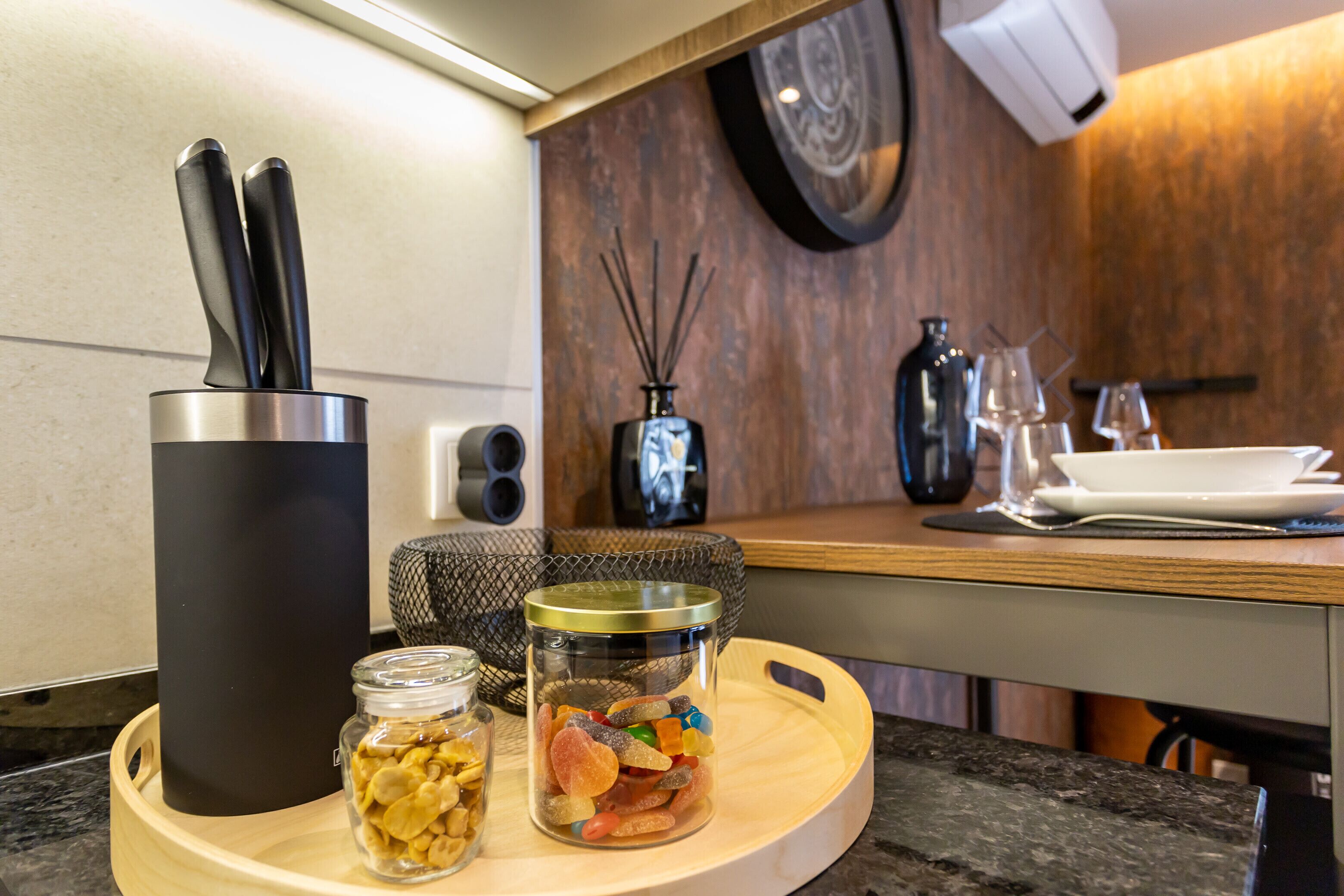 A kitchen counter with a coffee maker, a jar of cookies, and a jar of nuts.