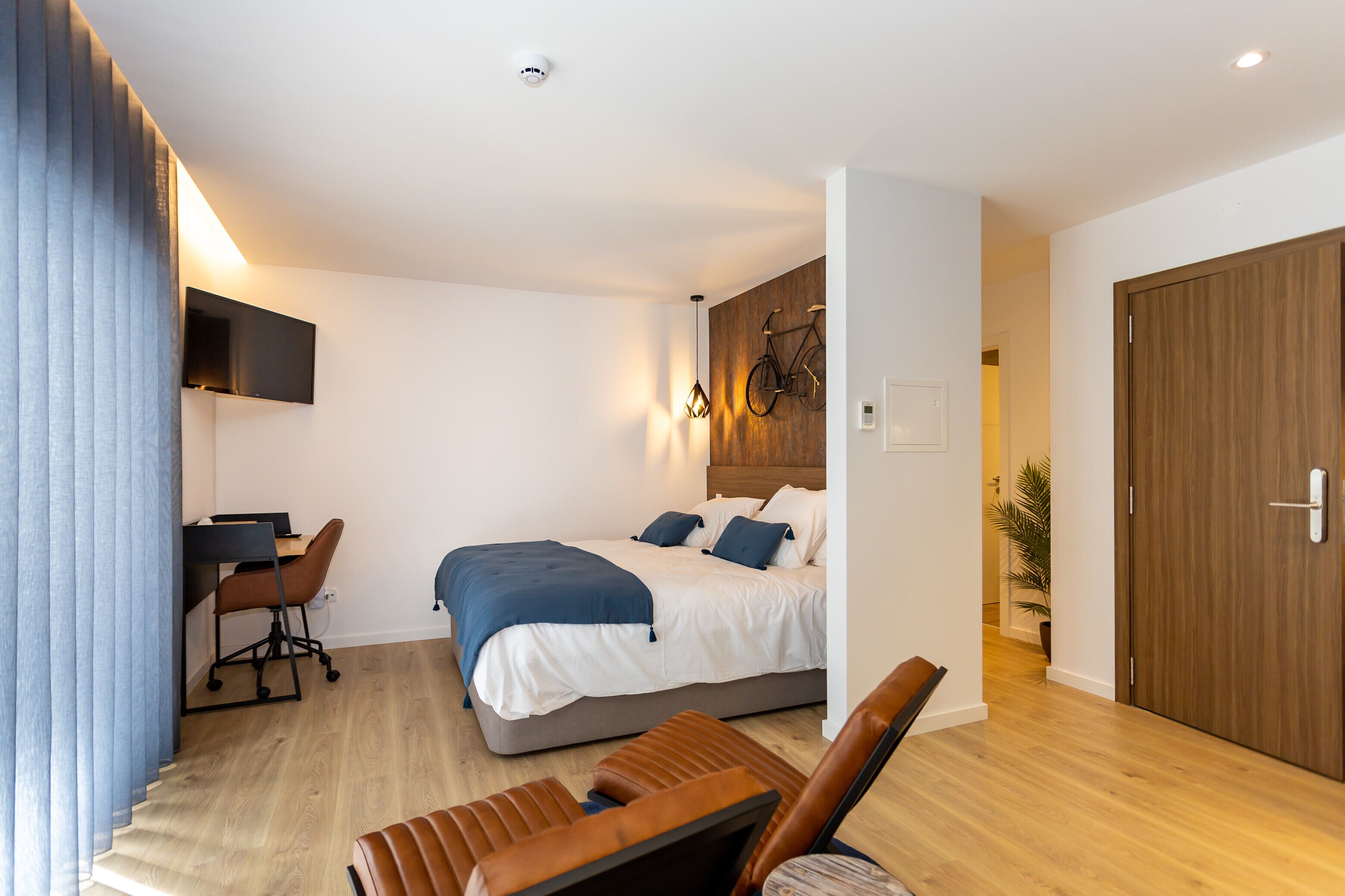 A modern bedroom with a bed, desk, and seating area.