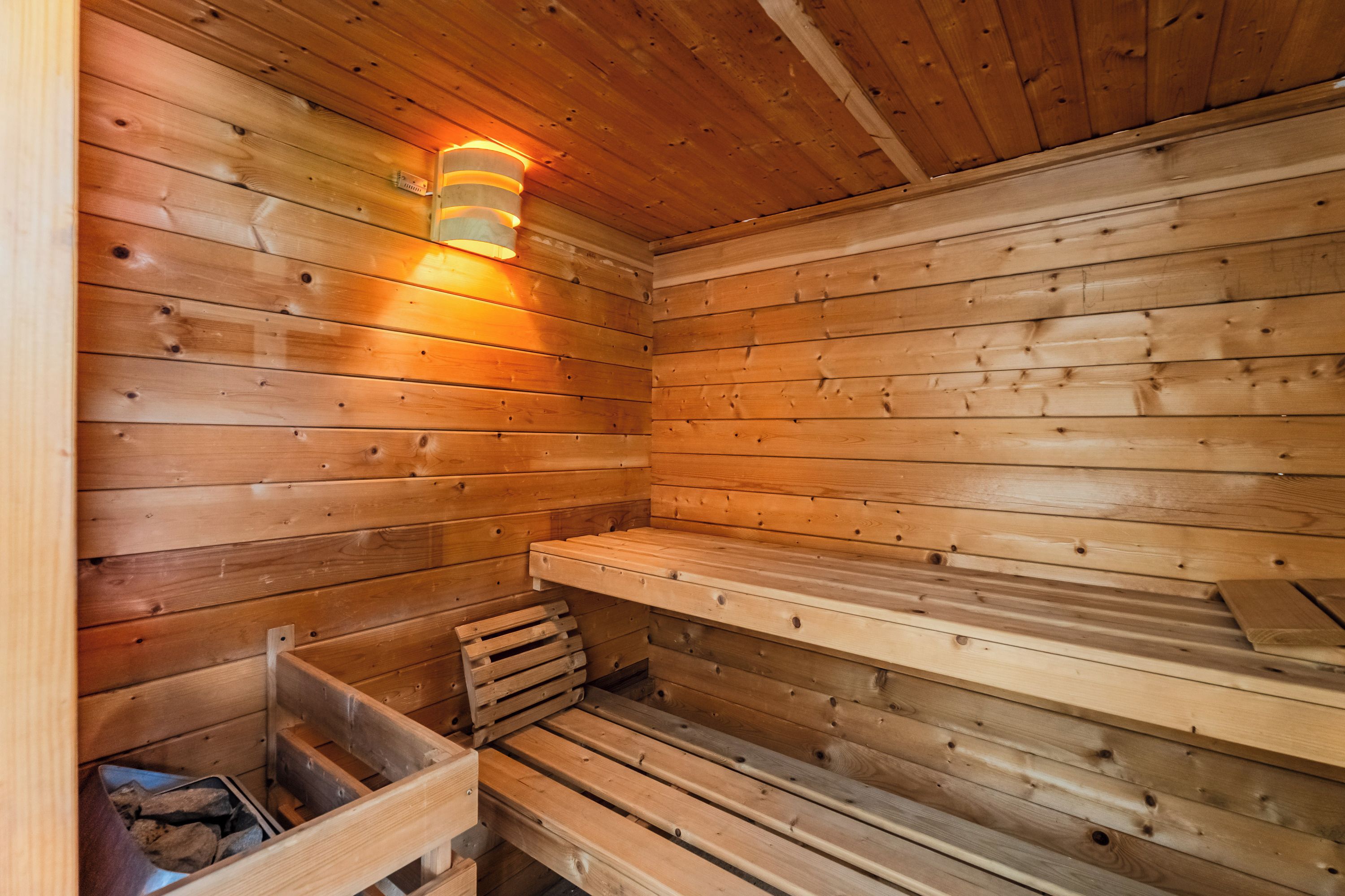 Una sauna de madera con bancos y una lámpara fijada a la pared.