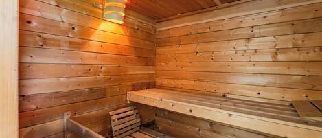 Una sauna de madera con bancos y una lámpara fijada a la pared.