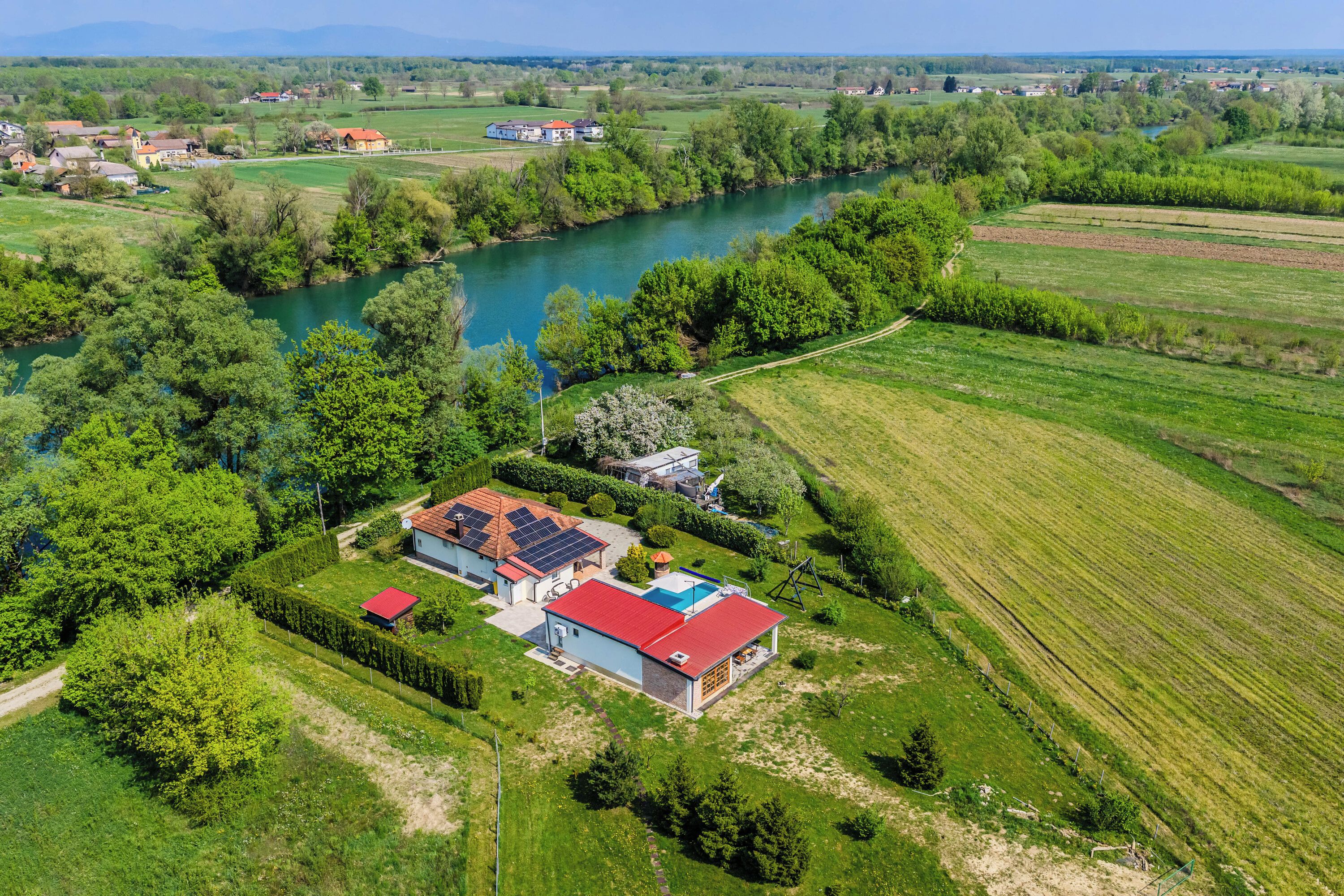 Een landelijk gelegen pand met een huis, zonnepanelen en een zwembad.