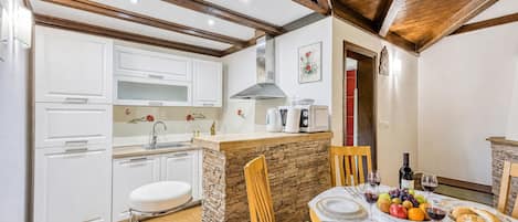 A compact kitchen with white cabinets, a stone island, and a dining area with a table set for two.