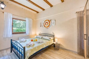 Une chambre à coucher avec un lit, une fenêtre avec des rideaux, une lampe de chevet et une œuvre d’art murale.