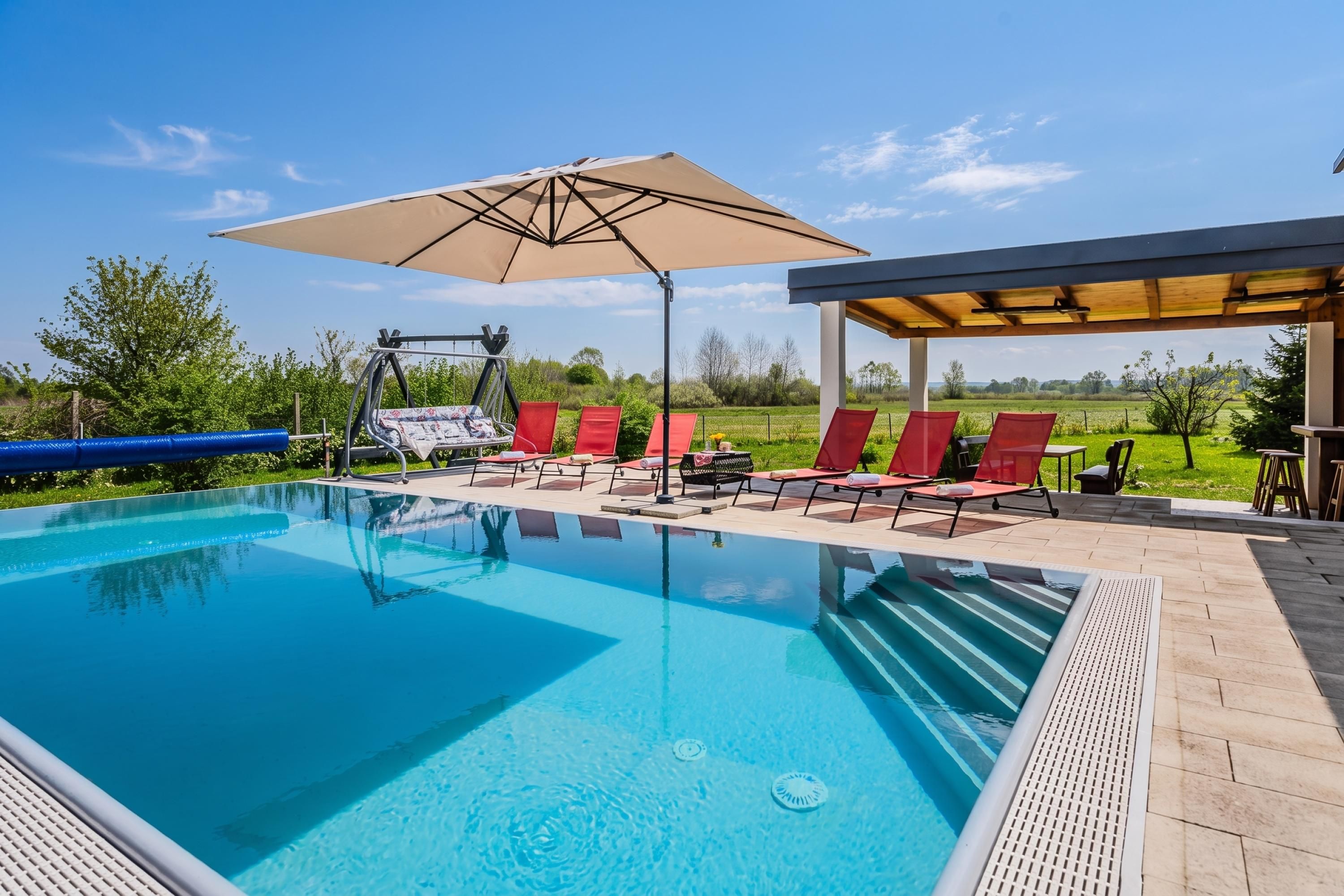 A swimming pool with lounge chairs and a pergola.
