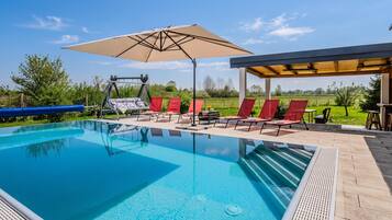 A swimming pool with lounge chairs and a pergola.