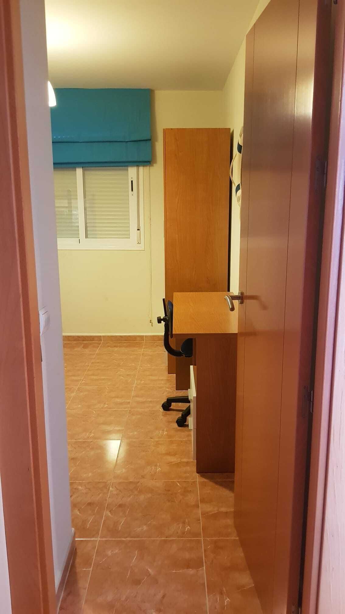 Une pièce avec une porte en bois, une fenêtre avec des stores et un sol carrelé.