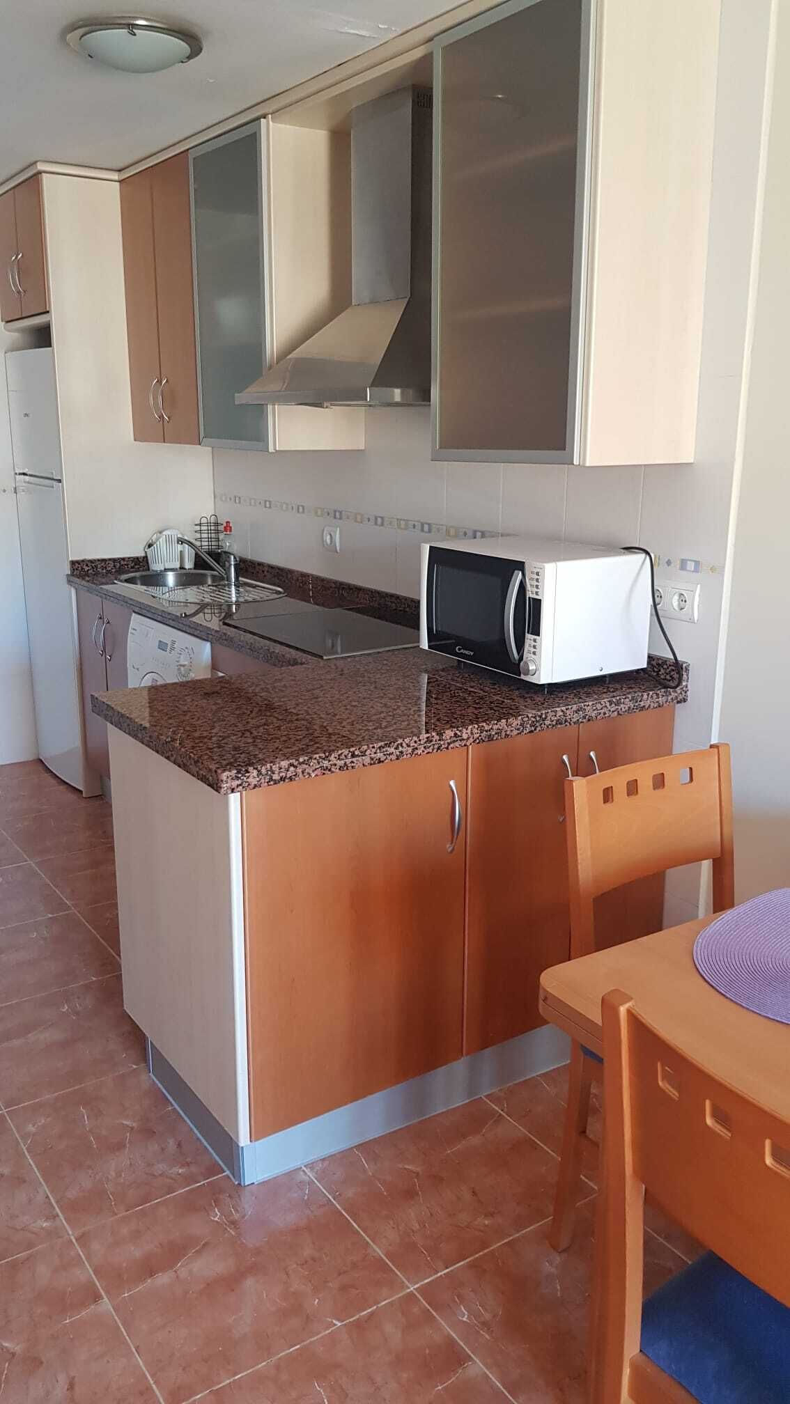 A compact kitchen with a microwave, sink, and a dishwasher.