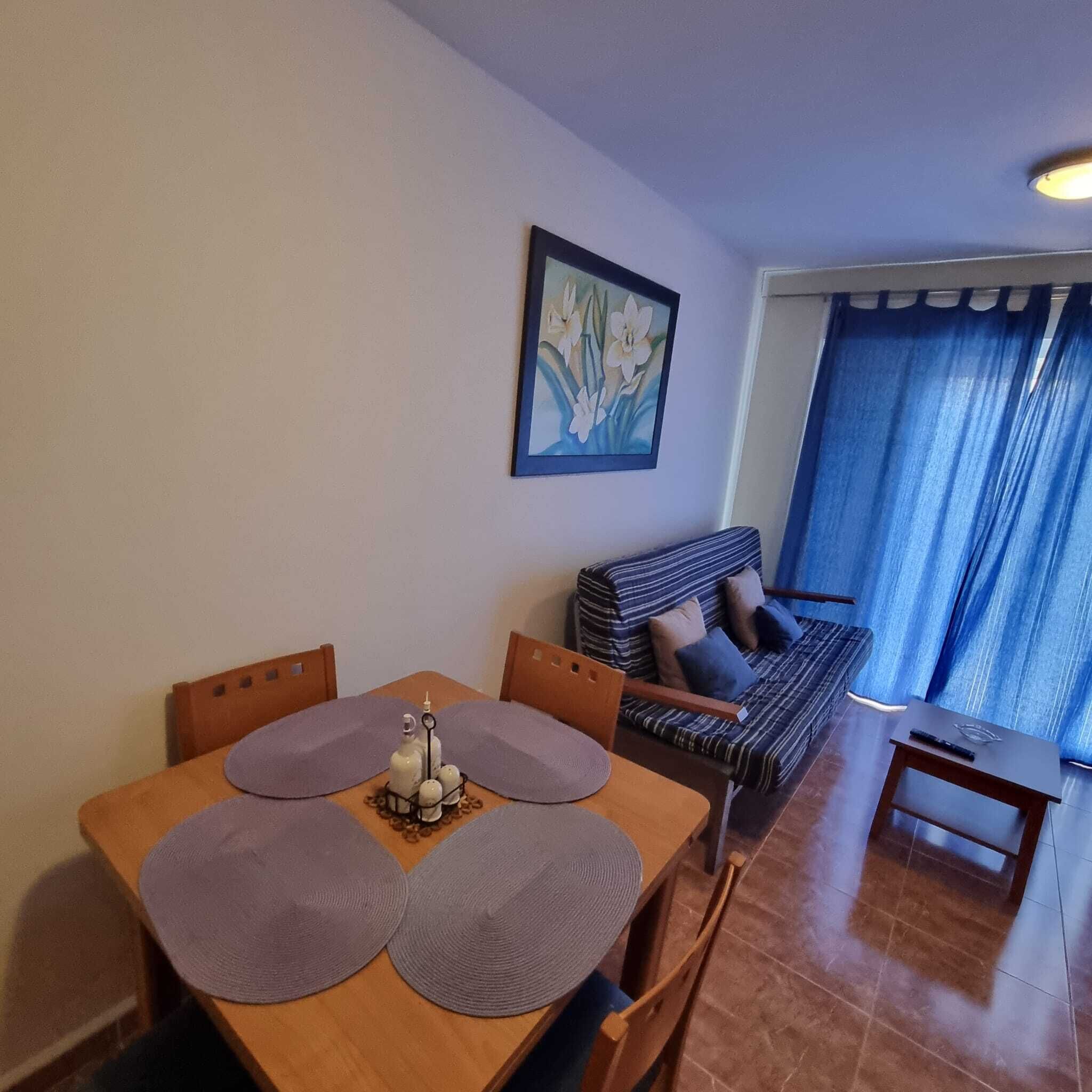Un área de comedor con una mesa, sillas, un sofá y un cuadro en la pared.