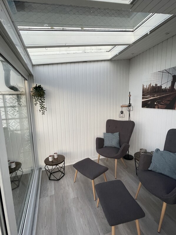 Un salon moderne avec une lucarne, un canapé gris, une petite table et une plante suspendue.