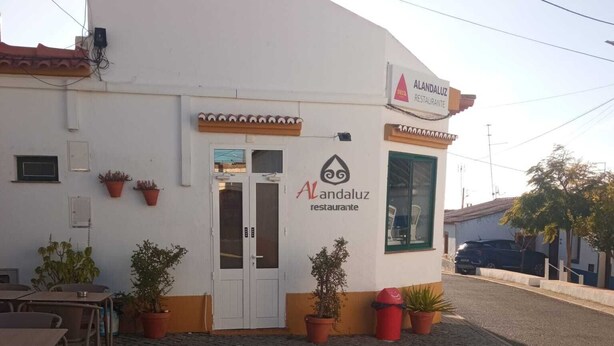 Um restaurante chamado 'Alandaluz Restaurante' com mesas ao ar livre e plantas em vasos.