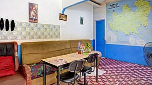 A room with a sofa, two chairs, a table with a notebook, a map on the wall, and a fan. - Hotel O Suci Homestay SyariahNearKilas 7 TV (Batam)