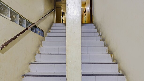A staircase with white steps and a central column, leading to a landing with a door. - Hotel O Suci Homestay SyariahNearKilas 7 TV (Batam)