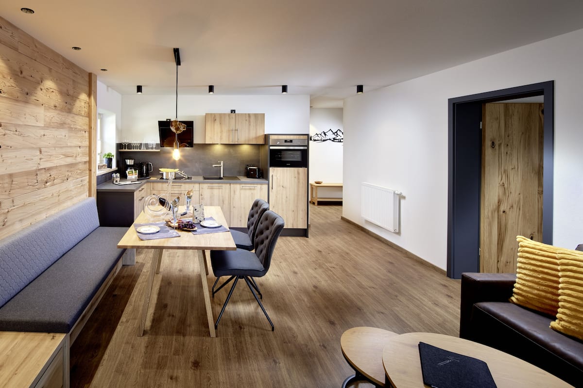 A modern kitchen with wooden cabinets, a dining table with chairs, and a built-in bench.