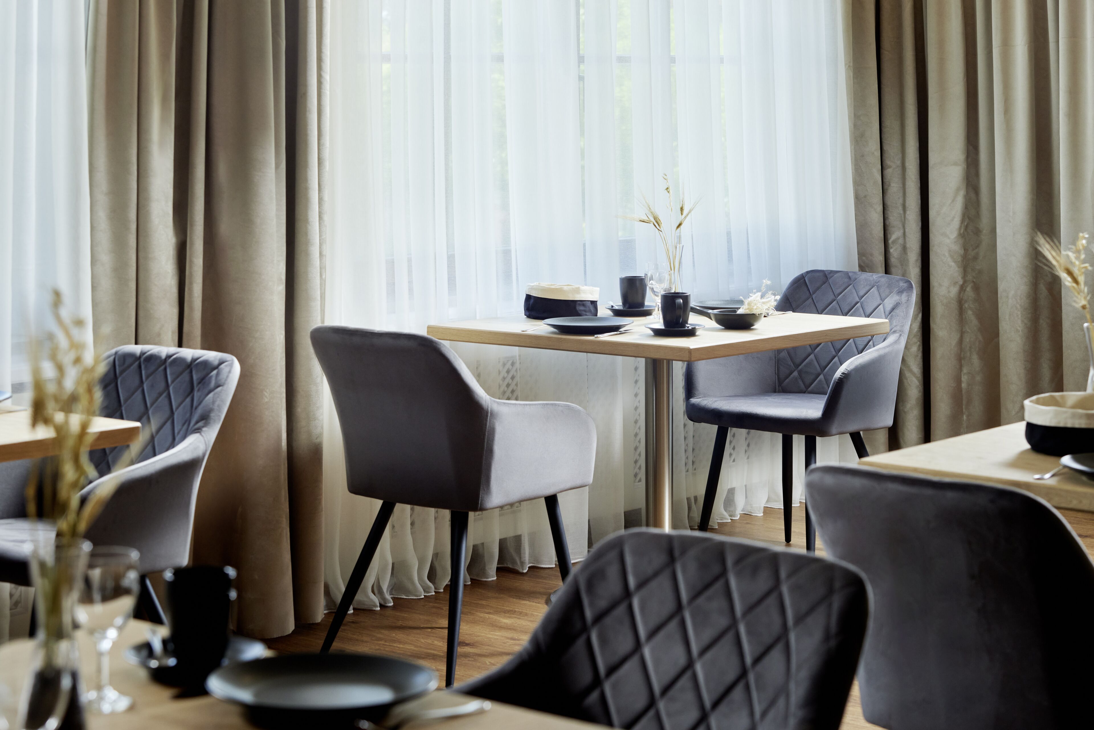 Un espace repas moderne comprenant une table, des chaises et un vase rempli de plantes séchées.