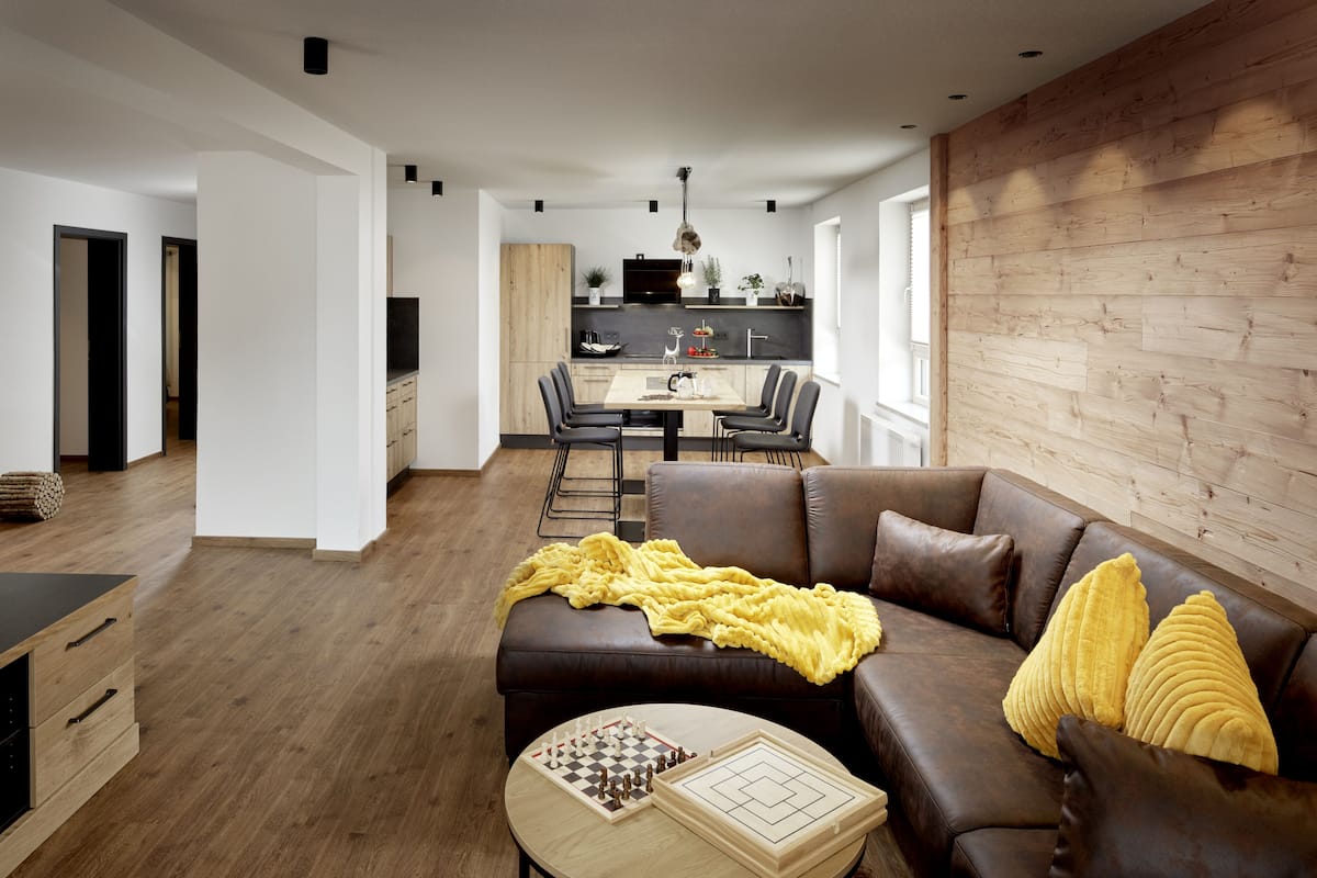 A modern living room with a brown leather sofa, a wooden coffee table, and a yellow blanket.