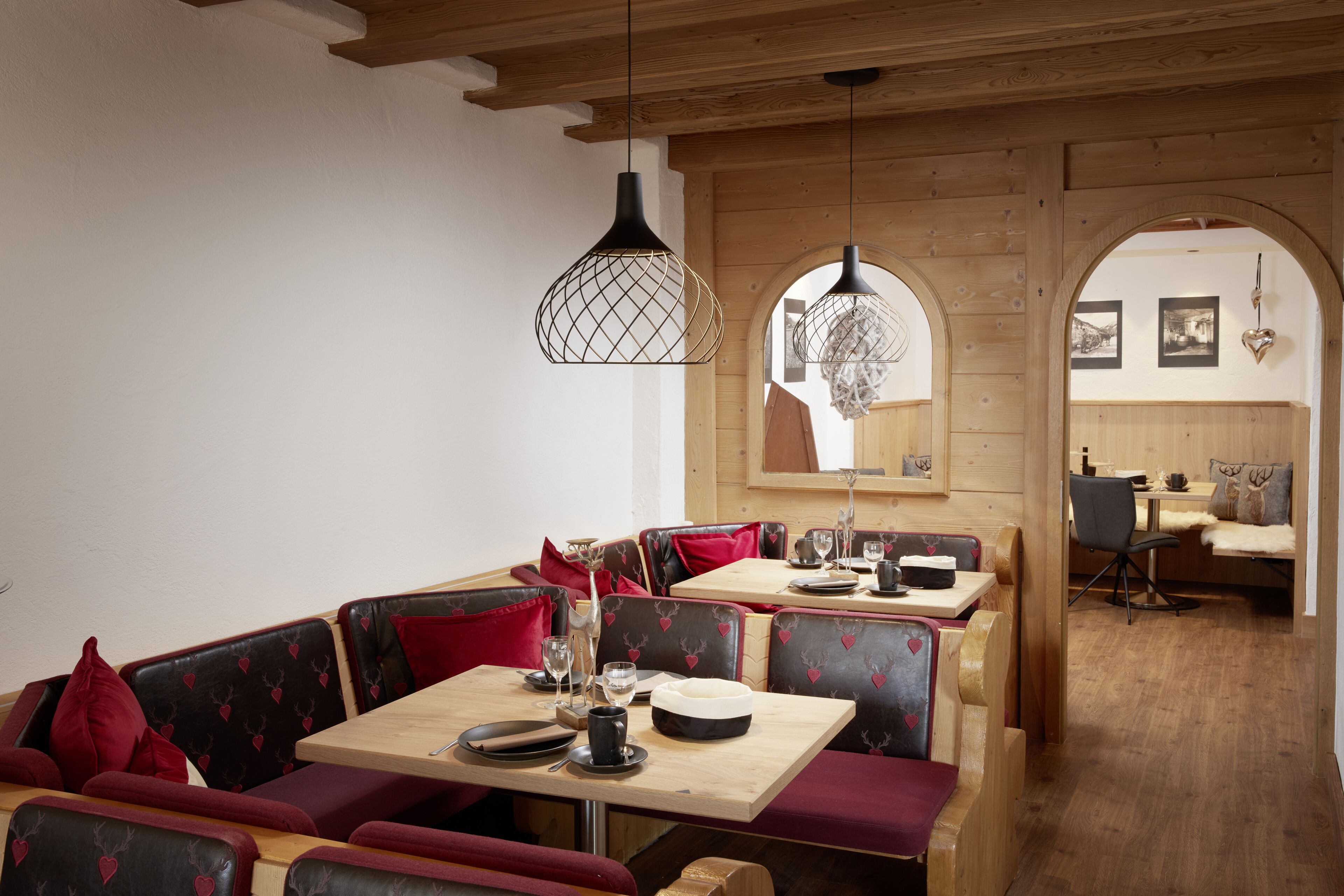 A restaurant with wooden booths, tables, and hanging pendant lights.