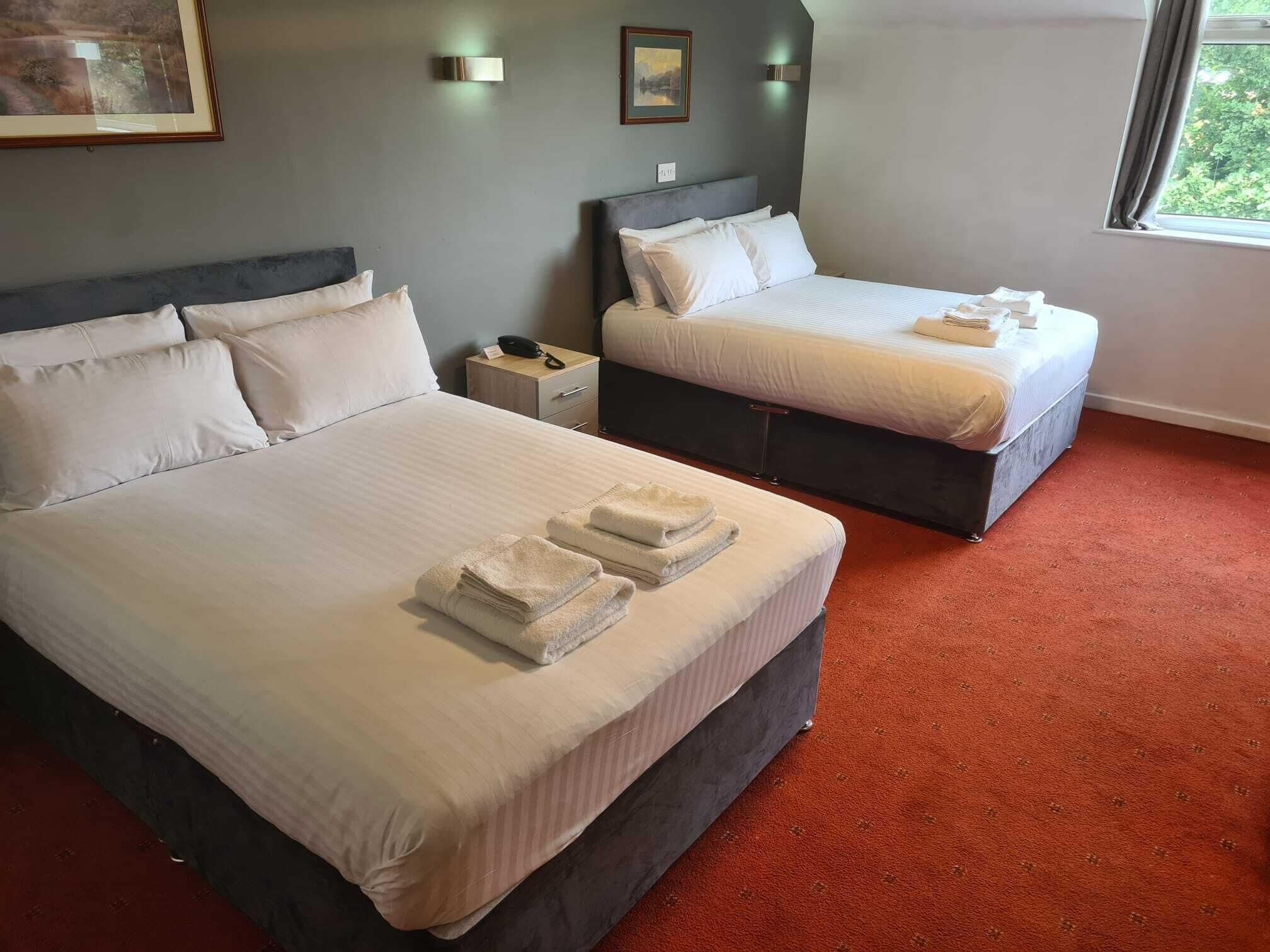 Une chambre d’hôtel avec deux lits, une table de chevet, un téléphone et une fenêtre donnant sur un beau paysage.